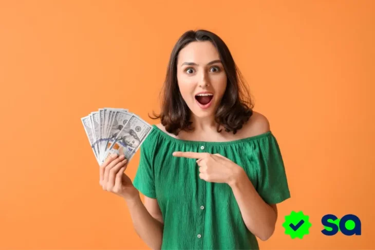 Mujer sorprendida sosteniendo varios billetes de euro, señalándolos, ilustrando la pregunta: ¿A dónde se va tu dinero?