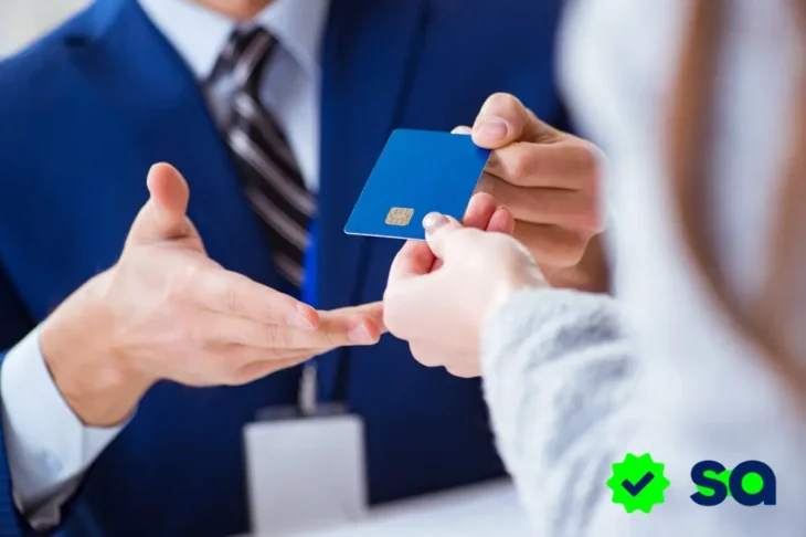 Persona entregando una tarjeta de crédito a un empleado, representando compras a plazo o en cuotas.