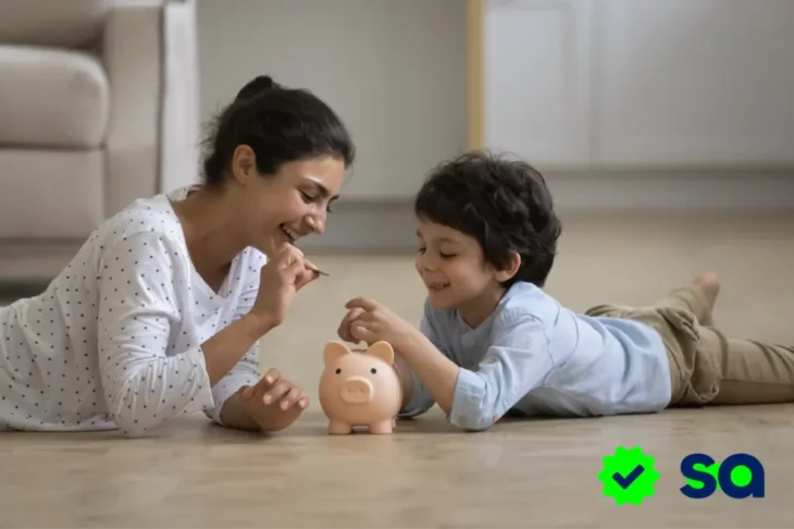 Mamás solteras enseñando a su hijo pequeño a ahorrar dinero usando una alcancía de cerdito.