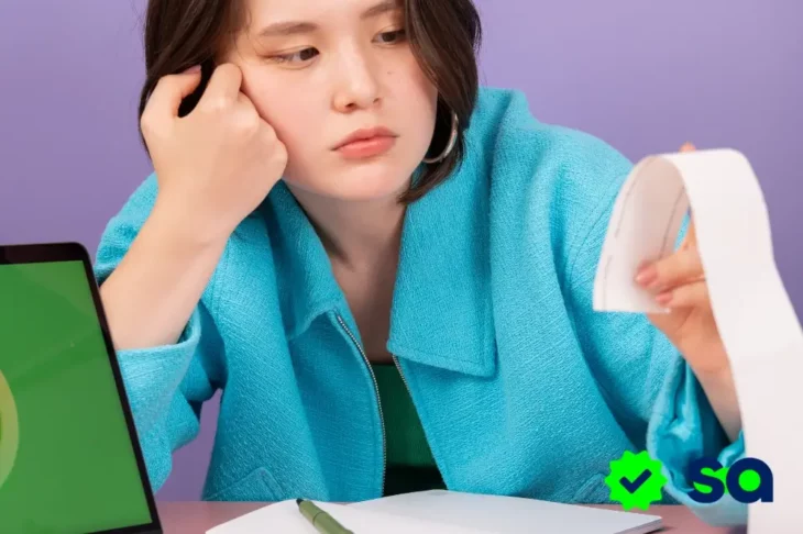 Mujer revisando un recibo preocupada por los números rojos en sus finanzas personales.