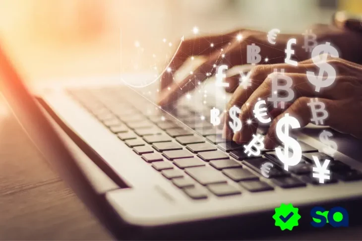 Manos escribiendo en un portátil con íconos de monedas flotantes, representando la transición del efectivo a la banca digital.
