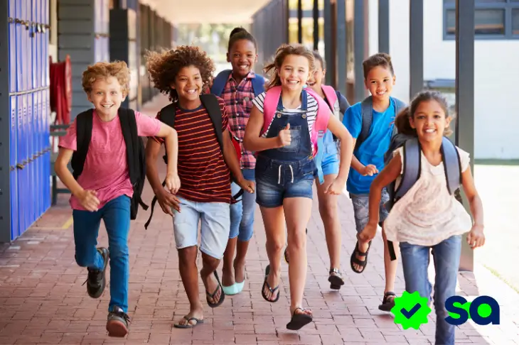 Grupo de niños corriendo felices en la escuela al comenzar las vacaciones escolares.