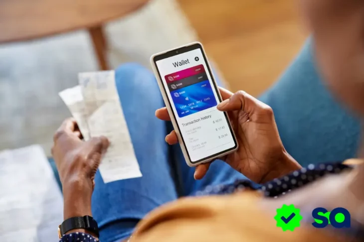 Persona usando su wallet digital en un teléfono inteligente mientras sostiene un recibo en la otra mano.