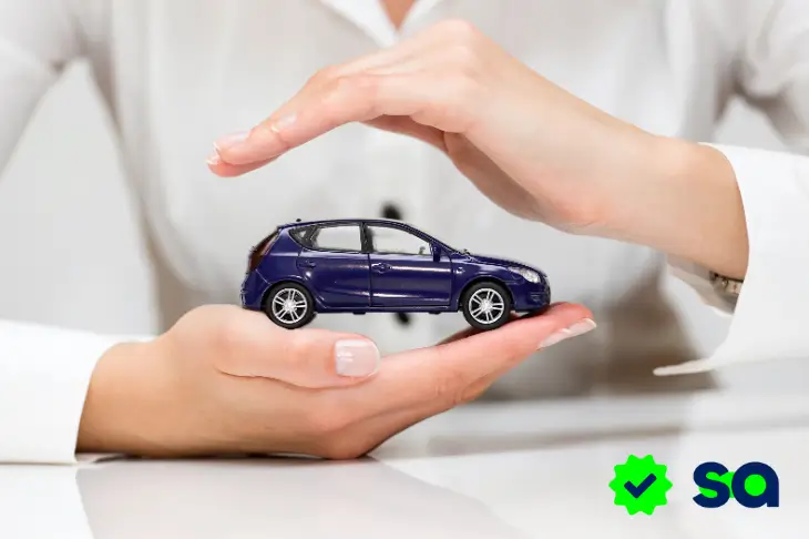 Manos protegiendo un coche en miniatura, concepto de seguro de automóvil.