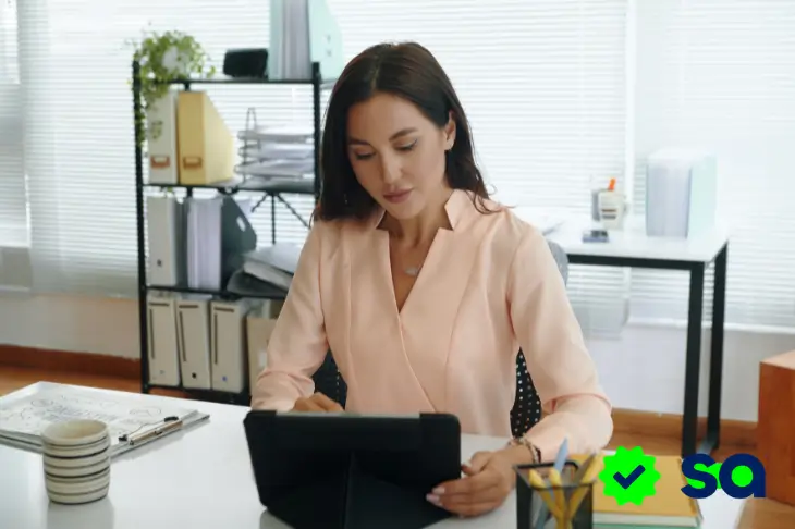 Ganar dinero con IA, mujer trabajando en una tableta en una oficina.