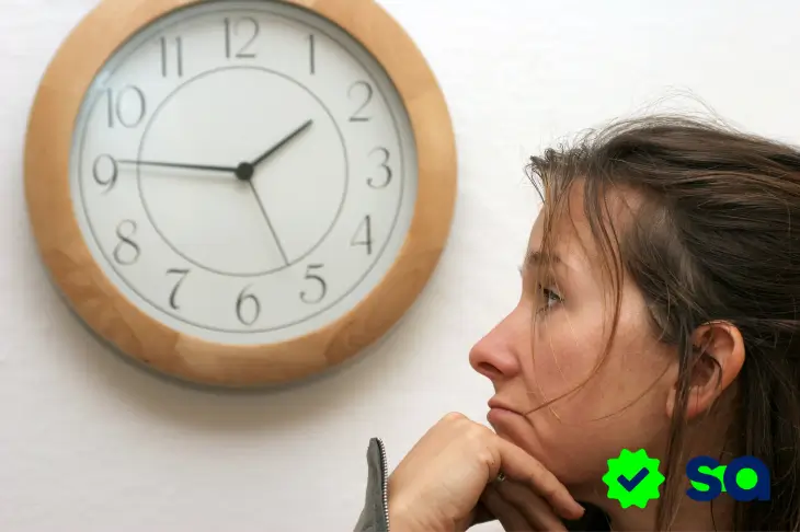 Autorización pendiente, mujer mirando un reloj de pared mientras espera la confirmación de un pago.
