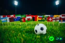 Banderas de diferentes países alrededor de un balón de fútbol en un estadio iluminado, representando la promoción Pásala para ganar rumbo al Mundial 2026™