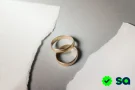 Divorcio representado por dos alianzas de matrimonio sobre una superficie rasgada, simbolizando la separación de una pareja.