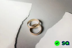 Divorcio representado por dos alianzas de matrimonio sobre una superficie rasgada, simbolizando la separación de una pareja.