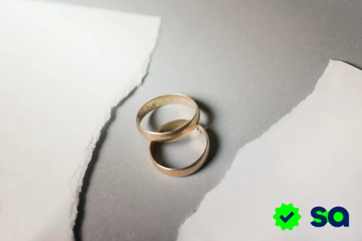 Divorcio representado por dos alianzas de matrimonio sobre una superficie rasgada, simbolizando la separación de una pareja.